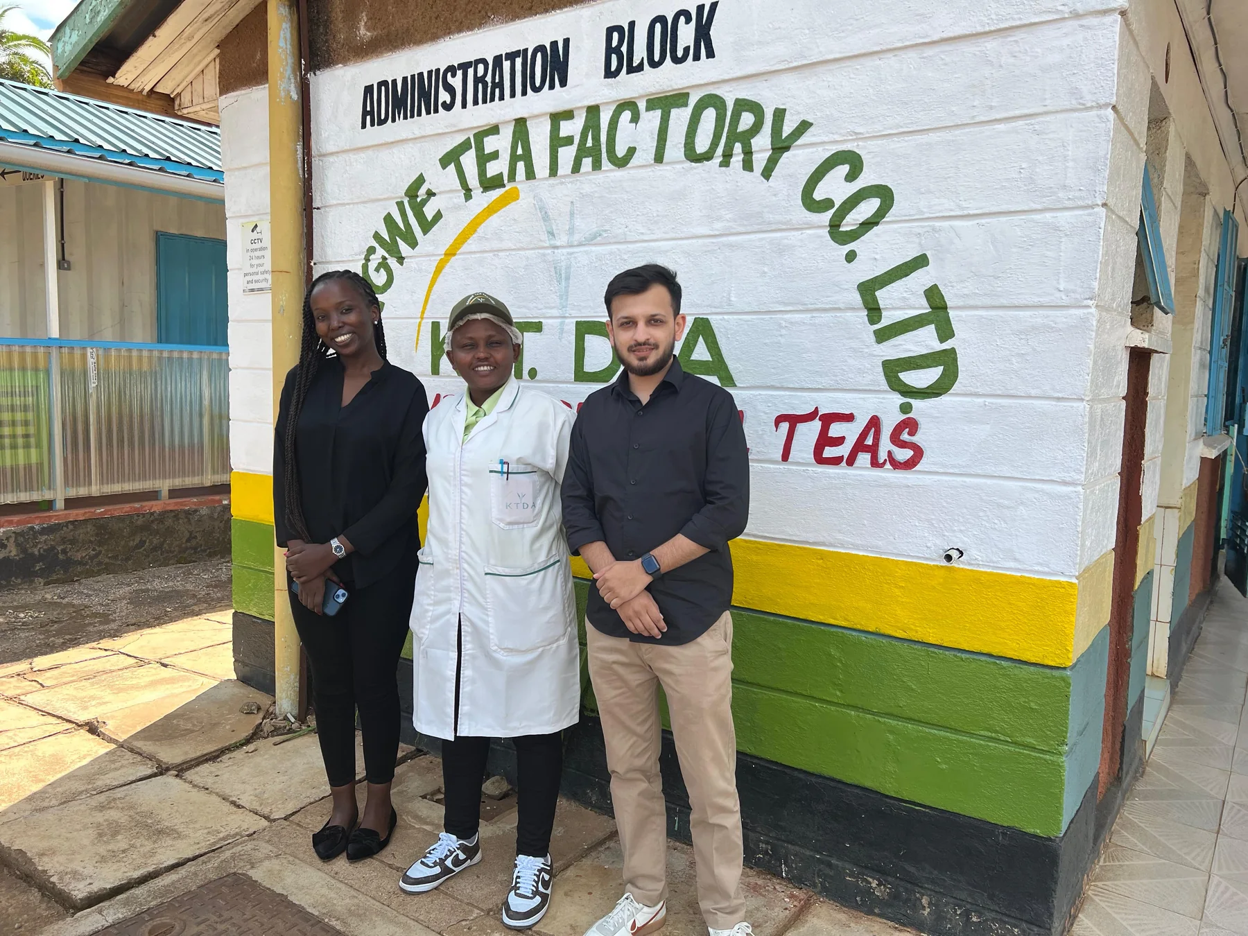 Tea-industry visitors outside a tea factory building